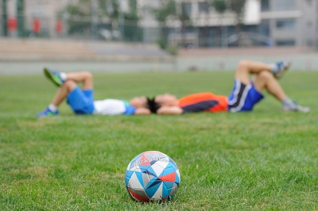 kids resting on soccer field grass