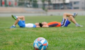 kids resting on soccer field grass